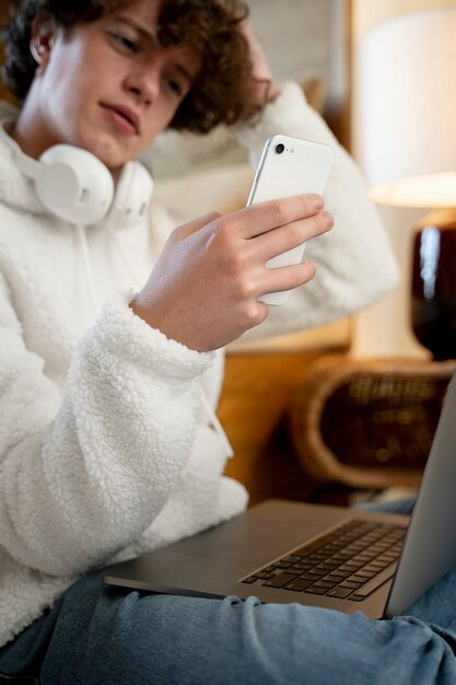 Teenager sitting in his bed and watching a video using his smartphone