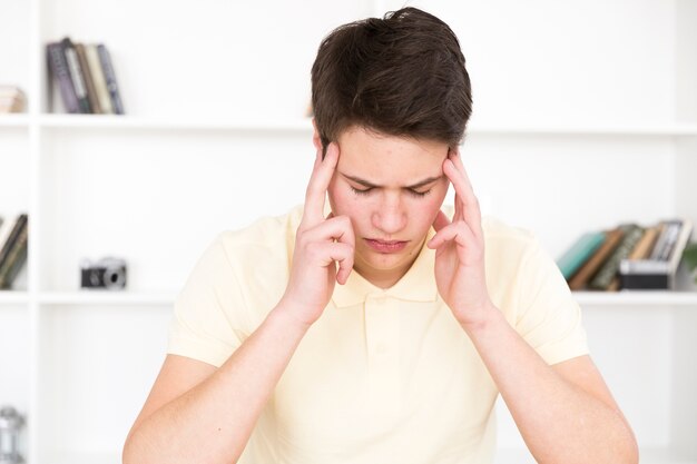 Teenager sitting holding fingers on temples