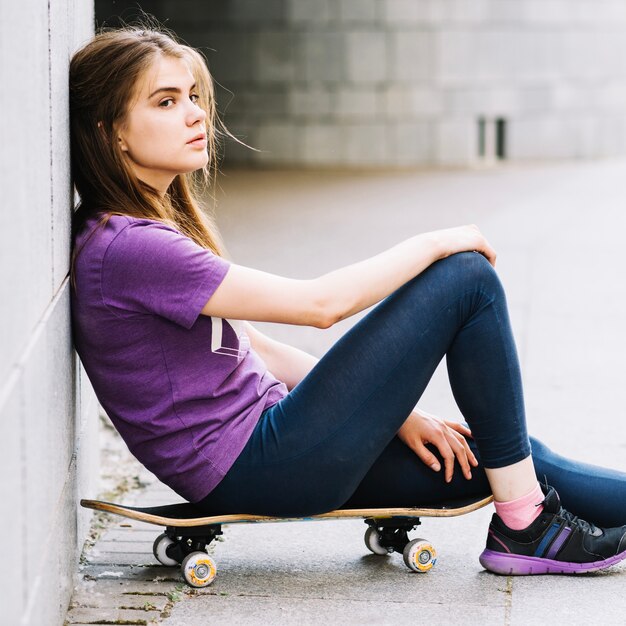 Teenager on skateboard leaning on wall