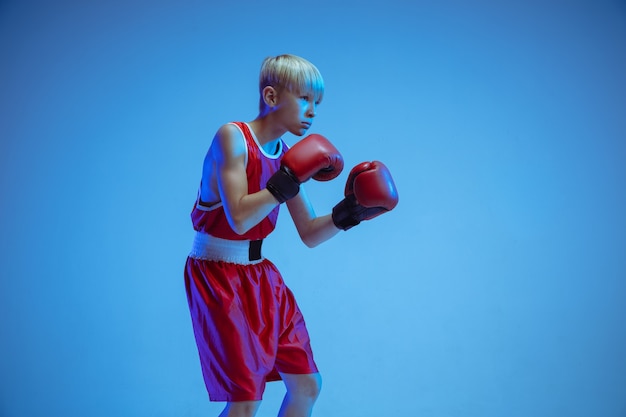 Free photo teenager in sportswear boxing isolated on blue studio wall