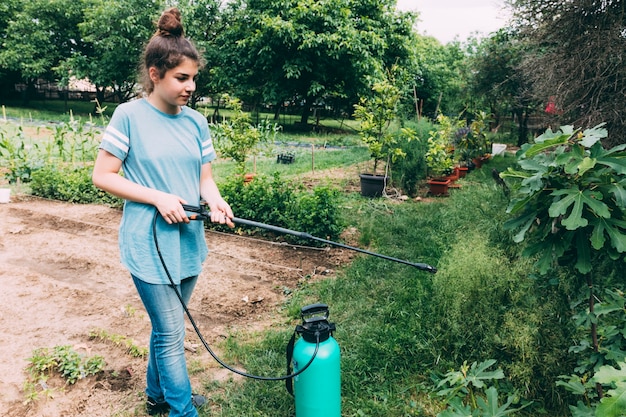 Teenager spraying plants in garden