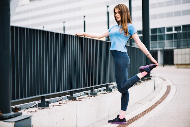 Teenager stretching leg near fence