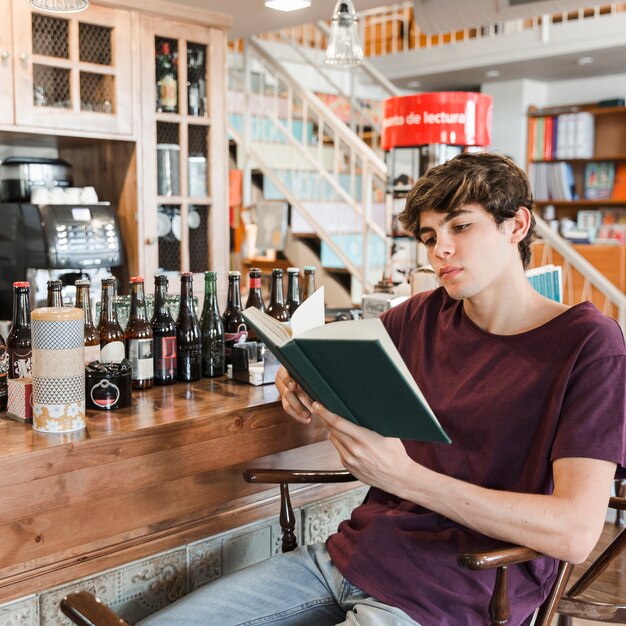 Подросток с книгой отдыха в кафе