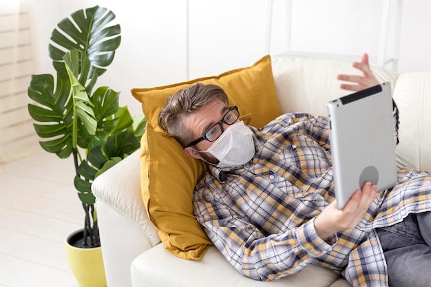 Teenager with face mask holding tablet