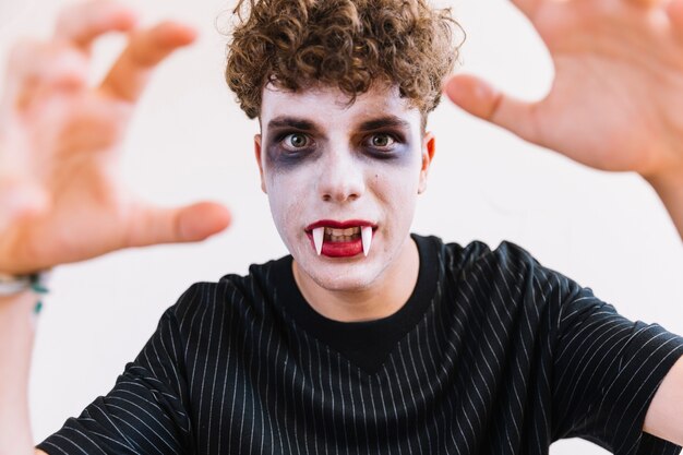 Подросток с хэллоуинским макияжем и вампирскими клыками