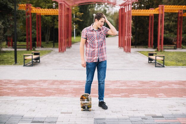 Teenager with skateboard in park