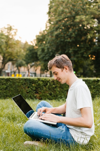Подросток работает на ноутбуке в парке
