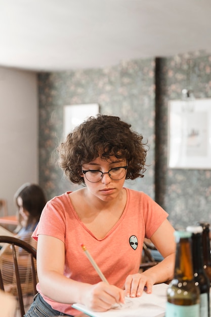 Foto gratuita scrittura dell'adolescente in taccuino al caffè