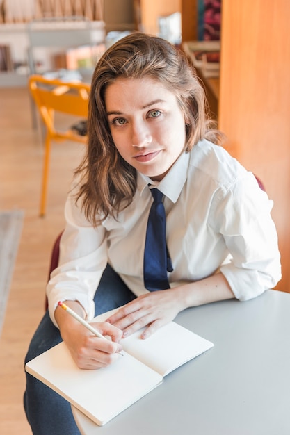 Teenager writing in notebook and looking at camera
