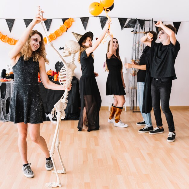 Teenagers in dark clothes smiling and dancing at party