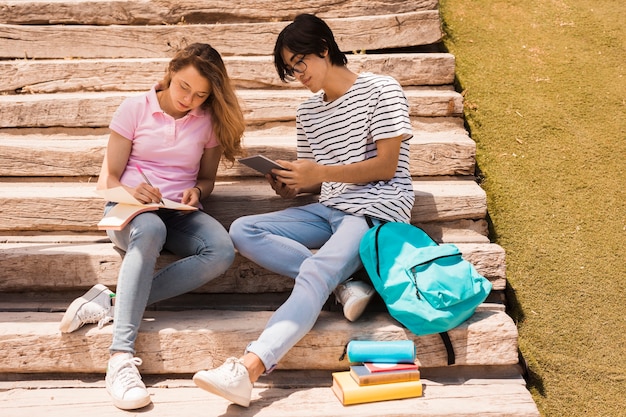 Teenagers doing homework together on stairs