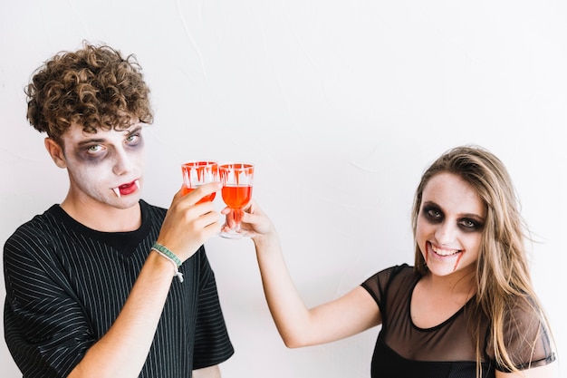 Free photo teenagers in halloween makeup drinking red liquid