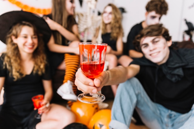 Teenagers on Halloween party drinking from glasses with painted blood