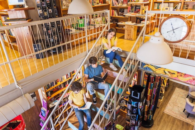 Teenagers reading on staircase in library