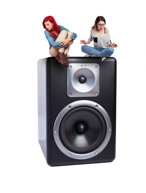 Free photo teenagers sitting on an enormous speaker