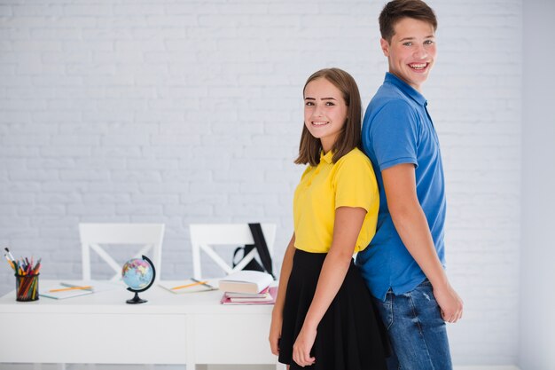 Teenagers standing back-to-back in classroom