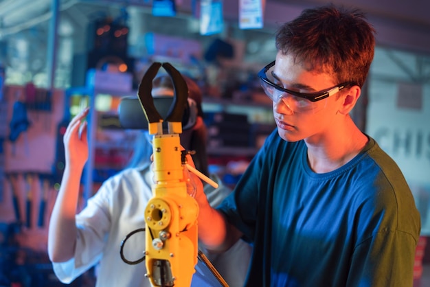 Foto gratuita ragazzi che fanno esperimenti di robotica in un laboratorio ragazzo con gli occhiali protettivi che tocca un robot