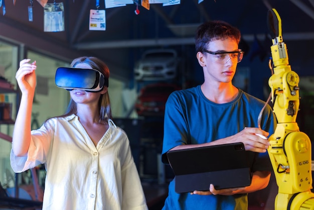 Teens doing experiments in robotics in a laboratory Boy in protective glasses using tablet and girl