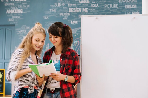 Teens reading book at whiteboard