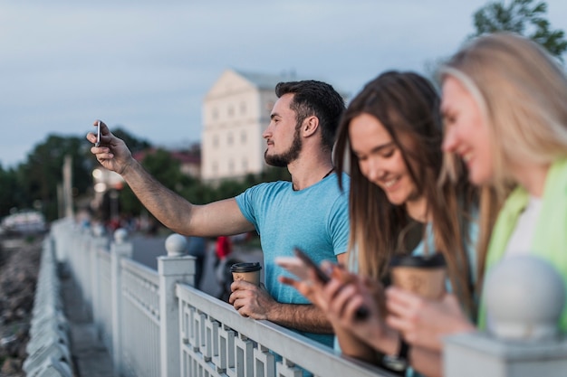 Foto gratuita ragazzi appoggiati su una ringhiera e scattare foto