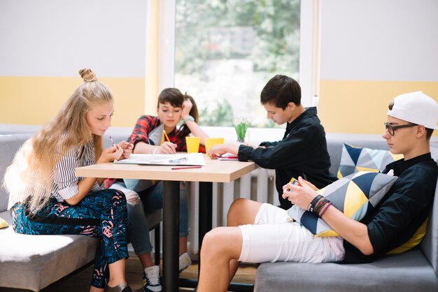 Подростки проводят время за столом в классе