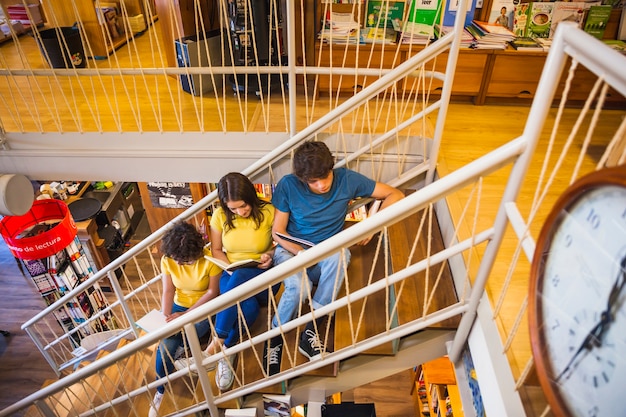 Teens with books relaxing on staircase