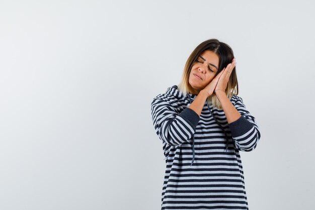 Teh young woman is showing sleeping gesture on white background