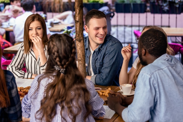 Telling jokes to close friends with informal atmosphere on the open air terrace of a cafe