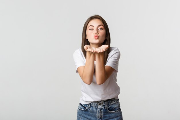 Tender attractive young woman blowing air kiss at camera flirty.