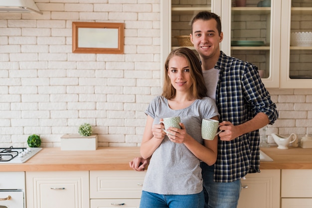 Tender bonding couple drinking brew and standing in kitchen 