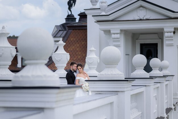 結婚式の日に愛の優しいカップルが建物の近くの屋外に立っています。