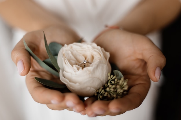Tender eustoma flower with engagement ring with tiny diamond in hands of bride