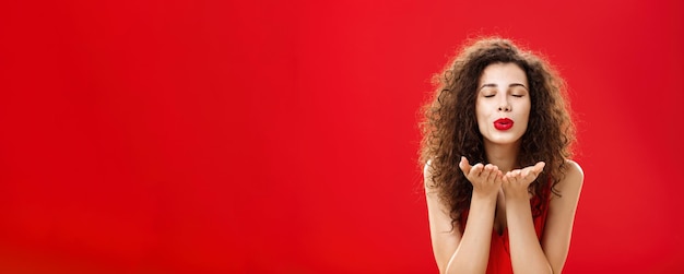 Free photo tender and gentle stylish caucasian girl with curly hairstyle and red lipstick bending towards camer