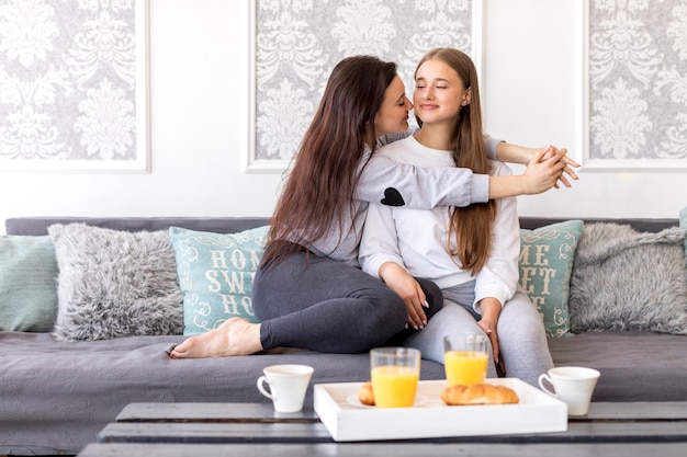 Foto gratuita coppie lesbiche teneri che si siedono sul sofà con la prima colazione