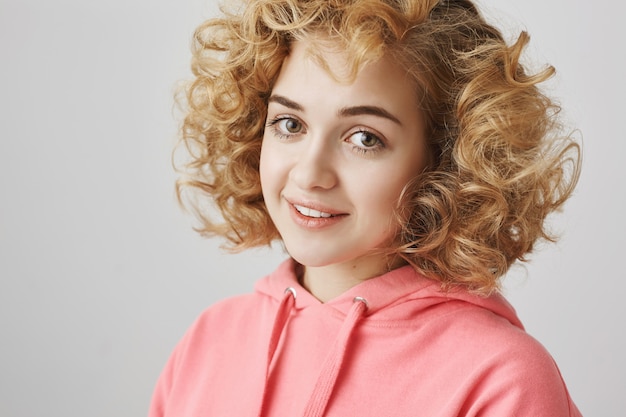 Tender lovely curly-haired girl smiling at camera