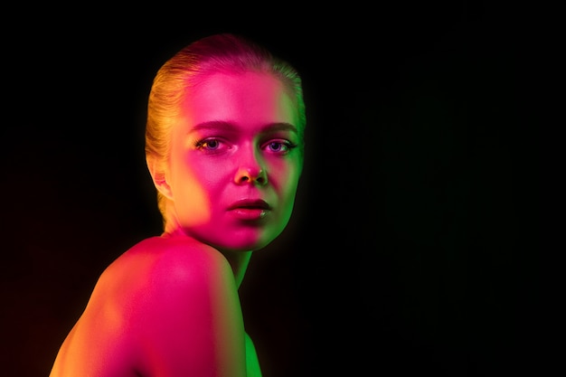 Tender. Portrait of female fashion model in neon light on dark. Beautiful caucasian woman with trendy make-up and well-kept skin