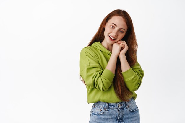 Tender redhead woman gazing and admire something, smiling romantic and adorable, standing in casual clothes against white background.