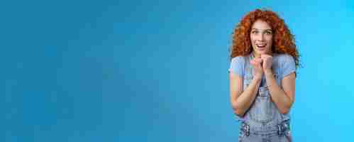 Free photo tender silly sensitive redhead emotive curly girl clench hands together touched smiling gasping see