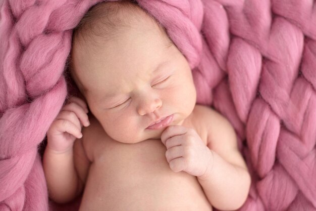 Tender sleeping newborn girl on coral pink salmon background closeup