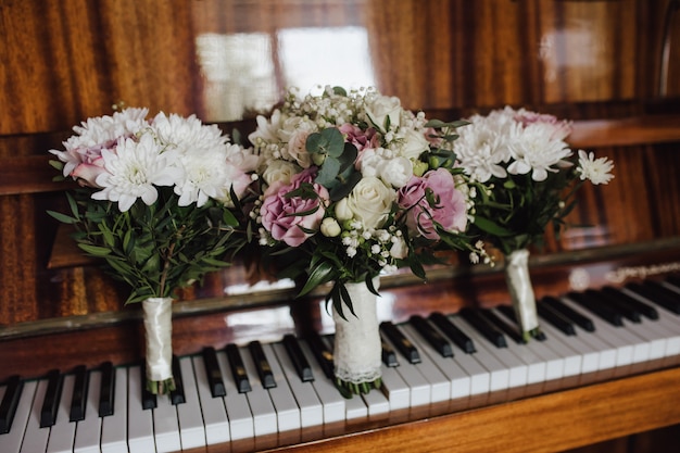 Tender wedding bouquets for bride and bridesmaids on the old fashioned piano