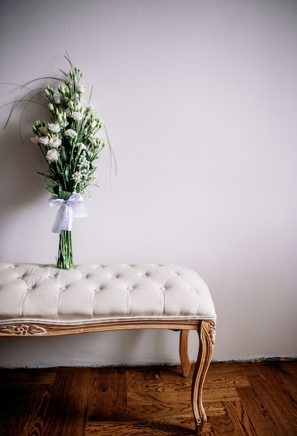 Tender white bouquet stands on a little sofa