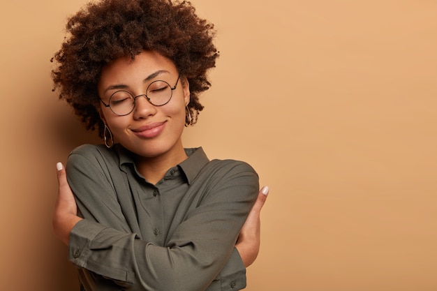 Free photo tender woman dressed in dark shirt, embrasses herself