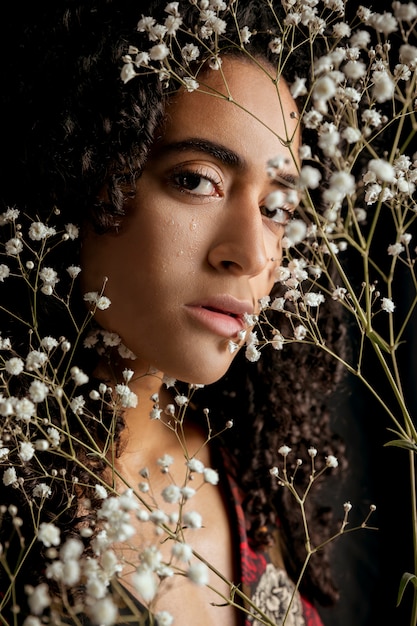 顔の近くの花の小枝を持つ優しい女性