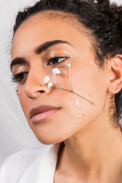 Tenera donna con fiore bagnato sul viso