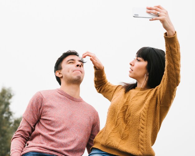 入札の若いカップルがselfieの準備をして