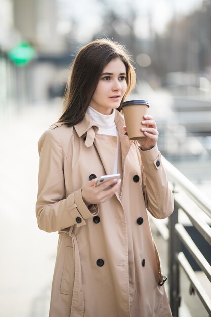 優しい若い女性が外の自分のカップからコーヒーを飲んでいます。
