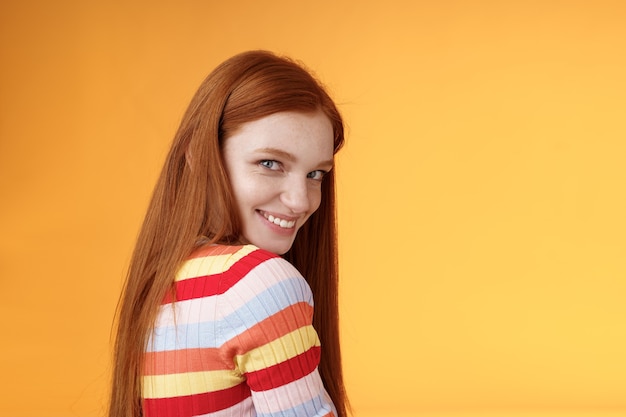 Tenerezza, romanticismo, concetto di seduzione. attraente sfacciato civettuolo giovane rossa audace ragazza voltarsi dietro sguardo macchina fotografica spalla sorridente risatina sciocco civettuolo esprimere simpatia affetto.