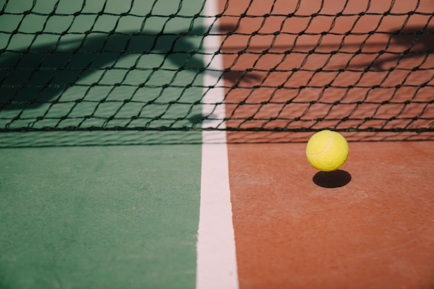 Free photo tennis ball in front of net with shadows