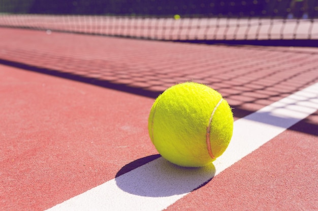 Теннисный мяч на теннисном корте с сеткой