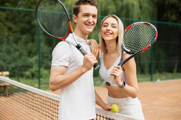 Tennis couple with rackets posing